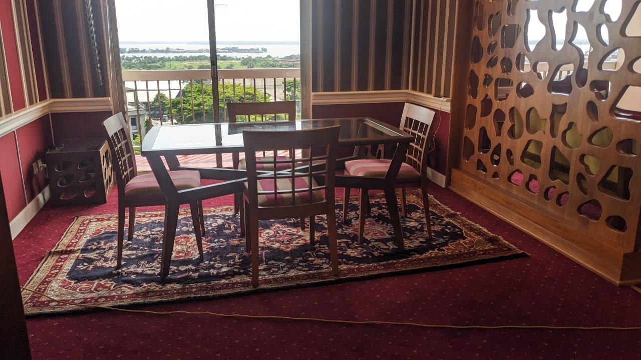 Coin repas d'une suite d'hôtel : table plateau verre, chaises et claustra ajouré